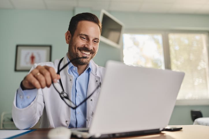 Arzt, der SEO für Ärzte betreibt und sich die Entwicklung seiner Websitebesucher am Laptop ansieht.